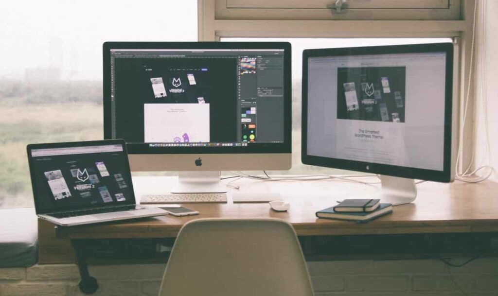 A laptop and two computers with screens that depict website development.